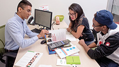 A member of the FIC staff showing a booklet to two students