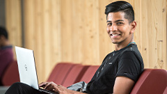 Photo of a male student holding a laptop